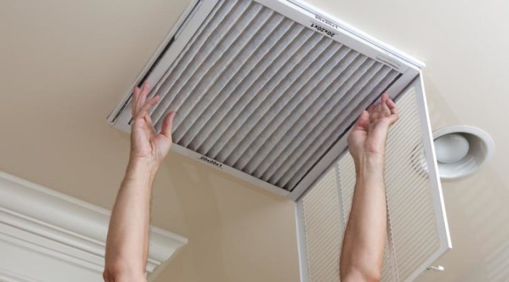 Person changing ceiling air filter