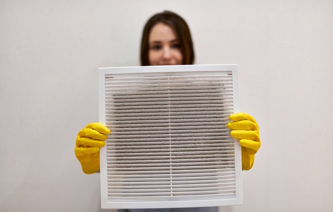 woman holding up a dirty air filter from an hvac unit