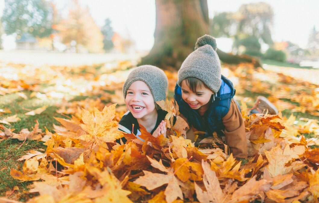 two young children playing in the fall leaves